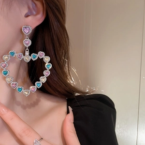 Gros plan de boucles d'oreilles cœur de luxe avec strass colorés portées par un mannequin