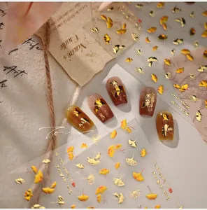 Detail of autumn ginkgo leaf nail art stickers with gold foil and warm orange relief