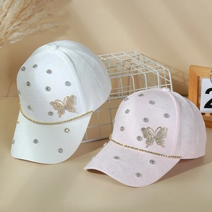 Close-up of stylish rhinestone butterfly decorations on white and pink baseball caps