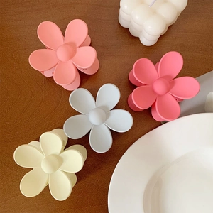 Detail of matte flower hair clips in various colors arranged on a wooden surface