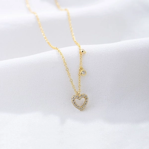 Macro shot of gold S925 silver hollow heart pendant set with sparkling white zircon stones