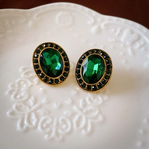 Close-up of vintage emerald oval earrings set on a white lace ceramic plate