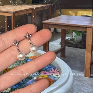 Boucles d'oreilles croix en argent avec perles blanches brillantes sur fond naturel épuré