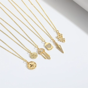 Close-up of gold necklaces with heart, honeycomb, and star compass pendant details