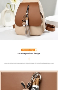 Detail of color-block backpack with brown flap, white body and cute rabbit charm accessory