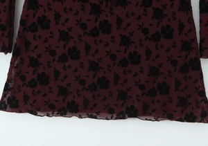 Close-up of wine red mesh fabric featuring black flocked floral pattern on the mini dress