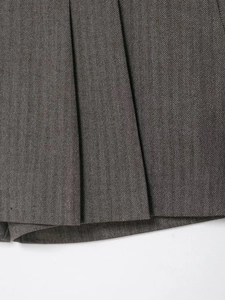 Close-up of grey herringbone fabric texture and pleated hem design of the mini skort