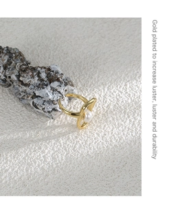Detail of a gold plated wavy ring with a white pearl on a natural coral background