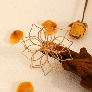 Detailed view of an oversized hollow gold flower ring placed on a rustic wood branch