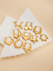 Detailed close-up of gold star and geometric titanium steel earrings set on white props