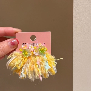 Close-up of handmade floral earrings with vibrant yellow and pink fringe tassels.