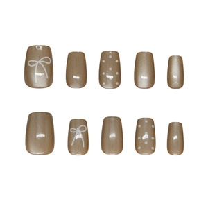 Press-on nail set in light coffee cat-eye pearl finish with white bow and polka dot patterns