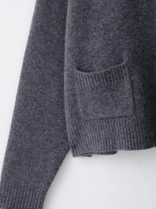 Détail du cardigan en laine gris foncé avec poches côtelées et texture de tissu raffinée