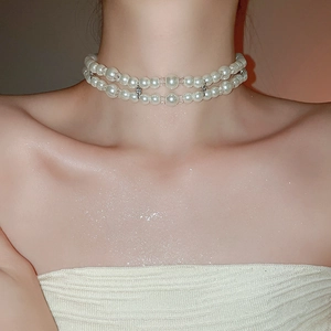 Close-up of elegant double-layered pearl choker necklace with a cross charm on skin