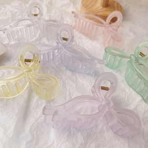 Flat lay of six colorful translucent frosted acrylic butterfly hair clips on white background