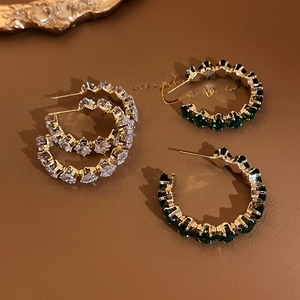 Detail view of retro C-shaped earrings with emerald and clear crystal stones