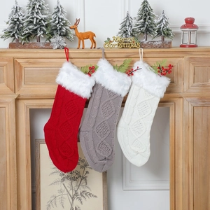 Trois chaussettes de Noël tricotées en rouge gris et blanc suspendues à une cheminée festive