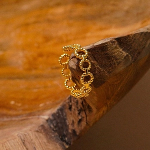 Macro view of a gold hollow chain ring with fine beaded texture on a wooden stand