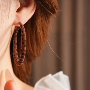 Gros plan de boucles d'oreilles rondes floquées léopard portées par un mannequin