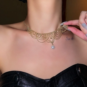 Detail of elegant gold layered fringe necklace with a white pearl pendant on model