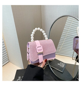 Pink mini crossbody bag with pearl handle and sparkling glitter finish shown in hand