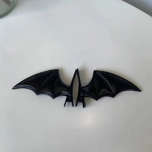 Detailed view of black bat wing hair clips made of textured faux leather for Halloween
