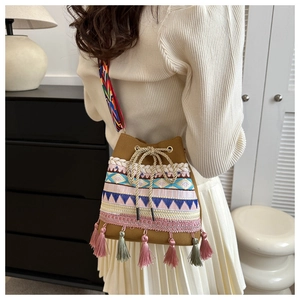 Ethnic style bucket bag with geometric embroidery, colorful tassels, and woven strap