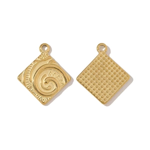 Détails de la texture martelée et de la gravure Moana sur les pendentifs dorés en acier