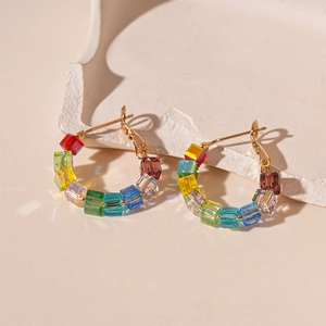 Detailed macro shot of colorful rainbow crystal square beads on golden earring hooks