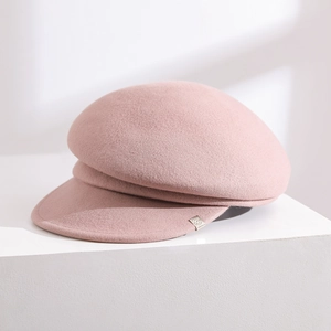 Detail of dusty pink wool felt baker boy hat with a refined side metal badge accent