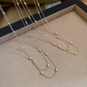 Detail of minimalist gold and silver beaded necklaces on a beige velvet display tray