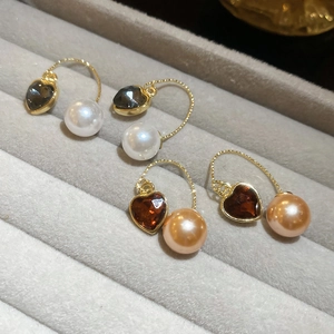 Détail de boucles d'oreilles cœur en cristal et perles dans une boîte grise