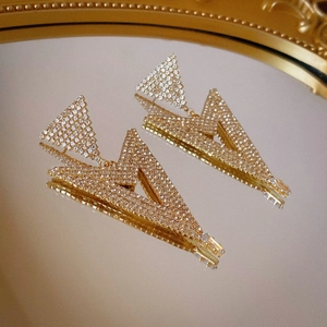 Macro shot of gold-plated geometric triangle earrings with shimmering cubic zirconia