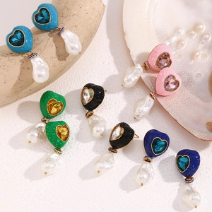 Detail of colorful heart-shaped earrings with baroque pearls and rhinestones on stone