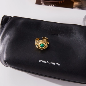 Detailed close-up of a vintage gold ring with green malachite stone on a leather surface