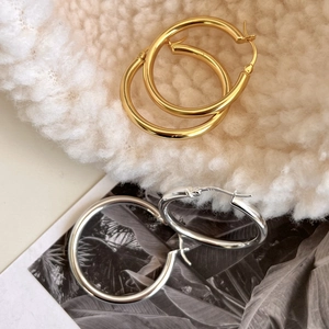 Polished 925 sterling silver hoop earrings in gold and silver finish on soft fabric