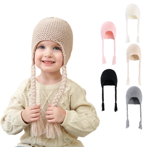 Detail of multi-color knitted baby hats with pom-poms and braided ear flaps