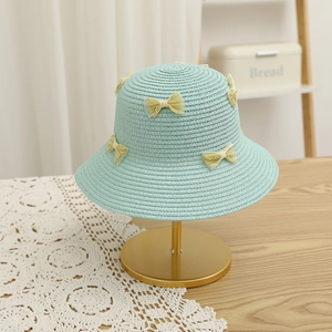 Detail of mint green straw sun hat with yellow lace bows on a golden display stand