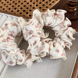 Close-up of floral print fabric scrunchie with lace texture in a beige jewelry tray