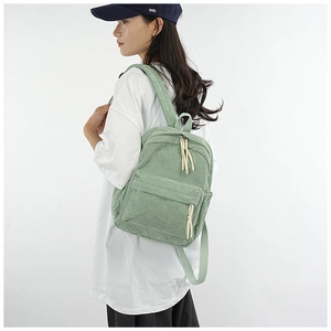 Back view of light green corduroy backpack on model showing casual school style