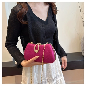 Close-up of pink glitter clutch with gold crystal clasp and chain strap held by model