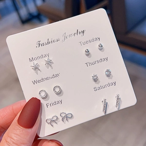 Close-up of 6 pairs of silver stud earrings with stars and rhinestones on a white card