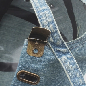 Detail der gewaschenen Denim-Textur und der verstellbaren Retro-Kupfer-Metallschnalle der Kappe