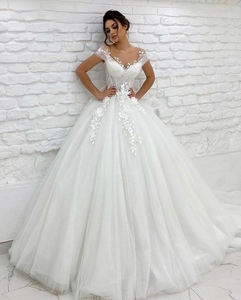Detail of white ball gown featuring intricate floral lace appliques and tulle skirt