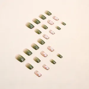 Faux ongles dégradés vert foncé avec paillettes argentées et motifs de fleurs de camélia