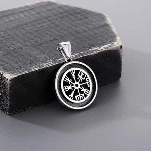 Detailed view of a silver stainless steel Viking Vegvisir compass pendant on wood
