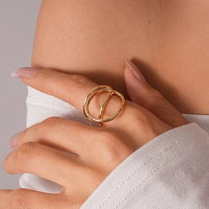 Macro view of gold geometric layered ring showing open hollow design on a model finger