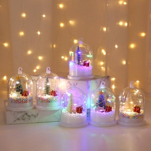 Detail of Christmas glass dome with mini tree, LED lights and foam snow on marble base