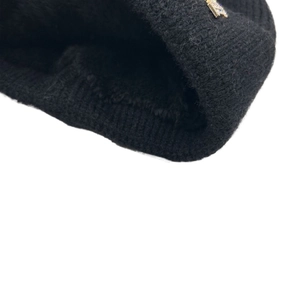 Dettaglio del berretto in maglia nera con emblema a stella dorata in strass sul bordo