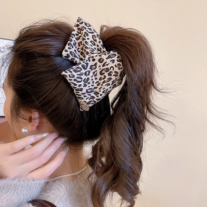 Detailed view of a vintage leopard print bow hair claw clip styled in a model's hair